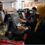 Woman cashier dealing with costumers ahead of Holy Fasting Month of Ramadan at utility store.