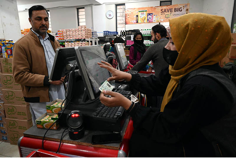 Woman cashier dealing with costumers ahead of Holy Fasting Month of Ramadan at utility store.