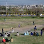 Youngsters watching and playing cricket at Faizabad interchange
