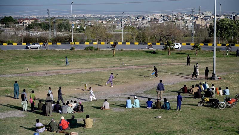 Youngsters watching and playing cricket at Faizabad interchange