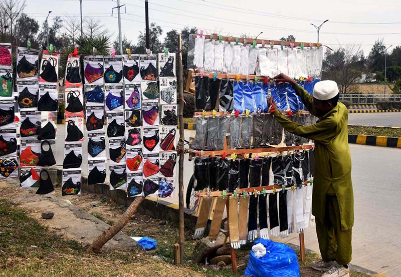 A street vendor arranging and displaying face masks at roadside