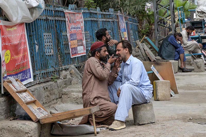 Roadside dental Quack extracting tooth of a patient.