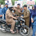 Chief Traffic Officer (CTO) Faisalabad Maqsood Ahmad Lone installing a kite string protector on a motorcycle for safety measure at Allied Chowk.