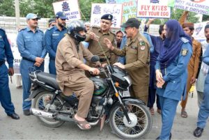 Chief Traffic Officer (CTO) Faisalabad Maqsood Ahmad Lone installing a kite string protector on a motorcycle for safety measure at Allied Chowk.