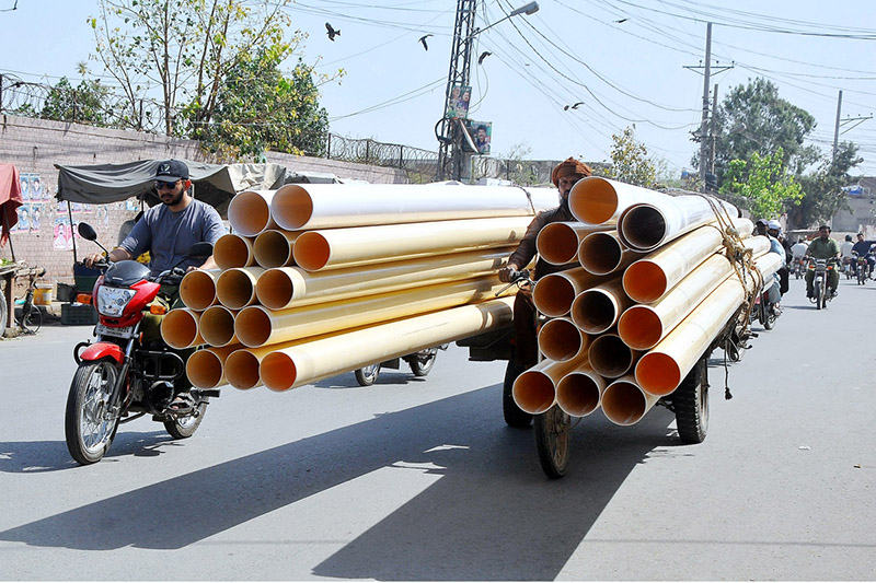 Tricycle Rickshaw holder is on the way loaded with huge plastic pipes at Masoom Shah Road.