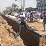 A student jumps to cross a dug out land for lay new electricity cables at Saddar.
