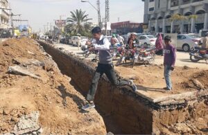 A student jumps to cross a dug out land for lay new electricity cables at Saddar.