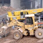 Labourers work on construction of IJP Road with the help of heavy machineries during development work in the city