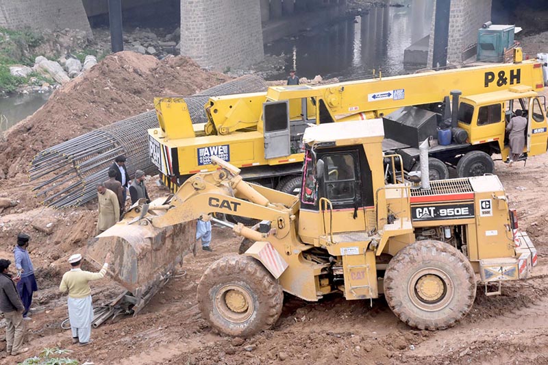 Labourers work on construction of IJP Road with the help of heavy machineries during development work in the city