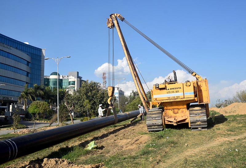 Labourer installing underground main Gas Pipe line with the help of heavy machinery at G-9 Peshawar More.