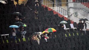 Cricket fans cover them with umbrellas to protect from rain at Rawalpindi Cricket Stadium as the Pakistan Super League (PSL) season nine T20 cricket match between Lahore Qalandars and Peshawar Zalmi called off due to rain and wet outfield