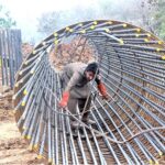A labourer fixing Iron bars to make frame for pillar of a bridge on IJP Road during development work in the city