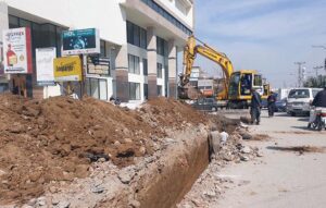A student jumps to cross a dug out land for lay new electricity cables at Saddar.