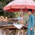 A street vendor displaying sweet potatoes to attract customers at his roadside setup on Chak Shahzad Road.