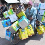 A motorcyclist on the way loaded with empty tin boxes at hilltop road.