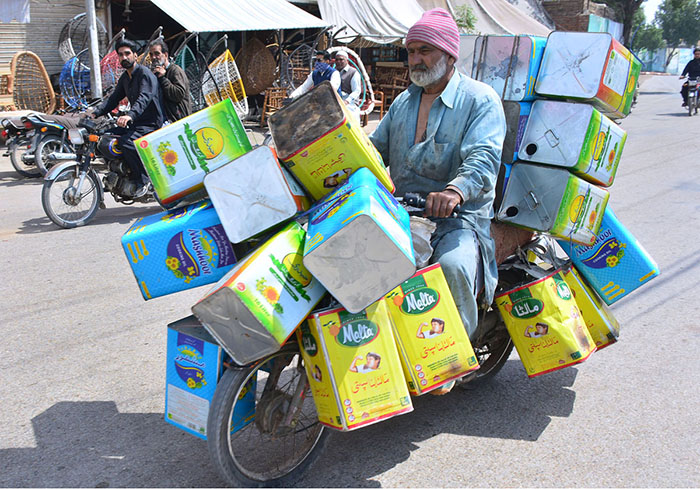 A motorcyclist on the way loaded with empty tin boxes at hilltop road.