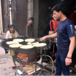 A vendor preparing traditional bread (paratha) at his setup in the city