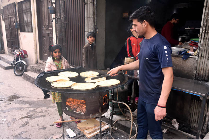 A vendor preparing traditional bread (paratha) at his setup in the city