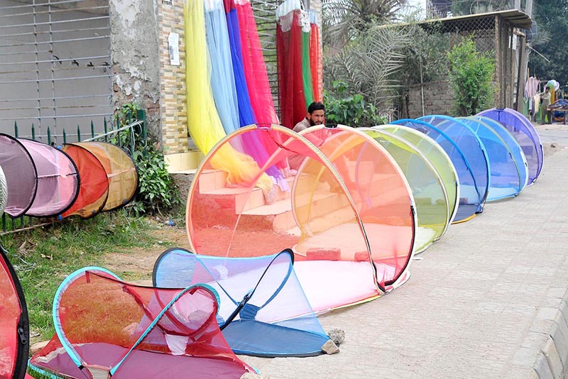 A vendor displaying mosquito net to attract customers at a roadside.