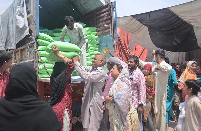 A large number of women standing in a long queue and waiting for their turn to purchase wheat flour on subsidized price provided by government in the city.