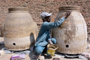 A worker busy giving final touch to clay made traditional oven (Tandoor) at his workplace
