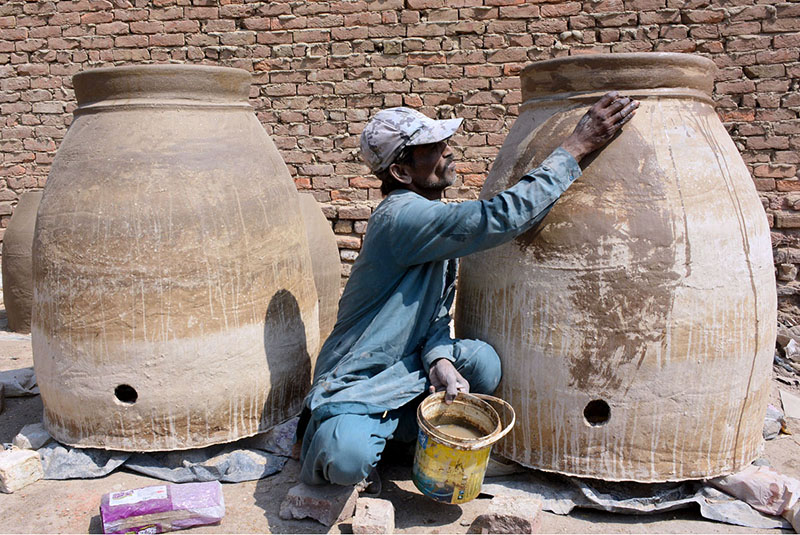 A worker busy giving final touch to clay made traditional oven (Tandoor) at his workplace