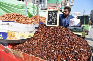 Vendor busy arranging and displaying different kinds of dates for selling on First Day of Holy Month Ramadan at Raja Bazaar.