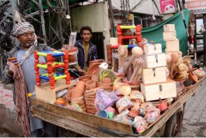 A vendor displaying clay-made and wooden items to attract customers at his setup in the city