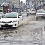 Vehicles passing through stagnant rain water accumulated on road during heavy rain that experienced the city