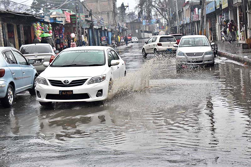 Vehicles passing through stagnant rain water accumulated on road during heavy rain that experienced the city