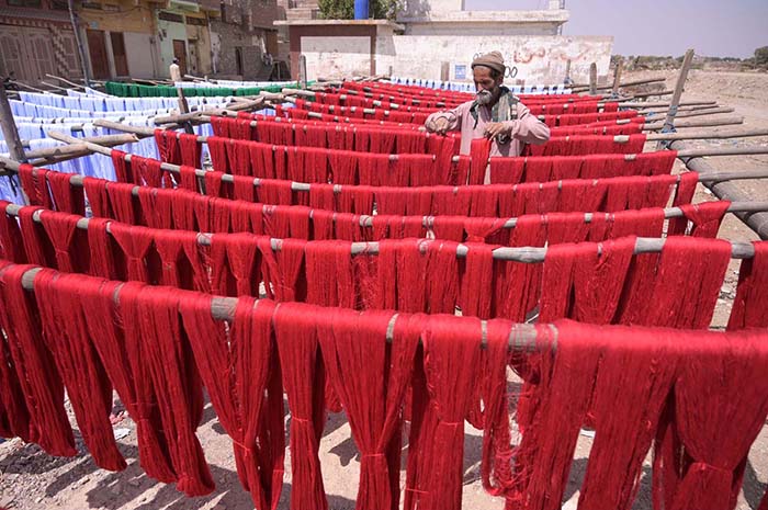 A labourer arranging threads for dry purpose outside Threads factory.