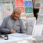 A worker is busy painting names on the marble piece at his workplace