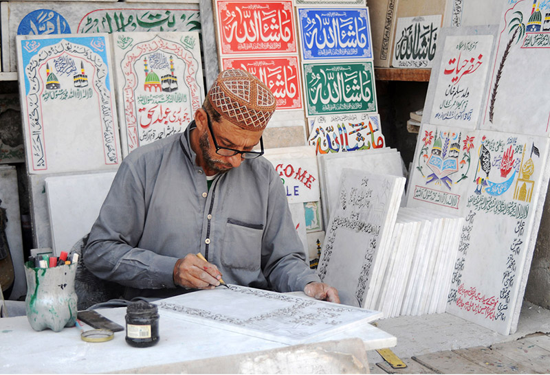 A worker is busy painting names on the marble piece at his workplace