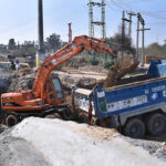 Labourers working construction of IJP Road with the help of heavy machineres during development work in the city.