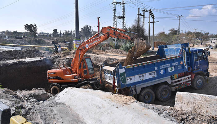 Labourers working construction of IJP Road with the help of heavy machineres during development work in the city.