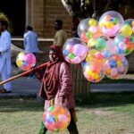 A girl selling balloons at a park.