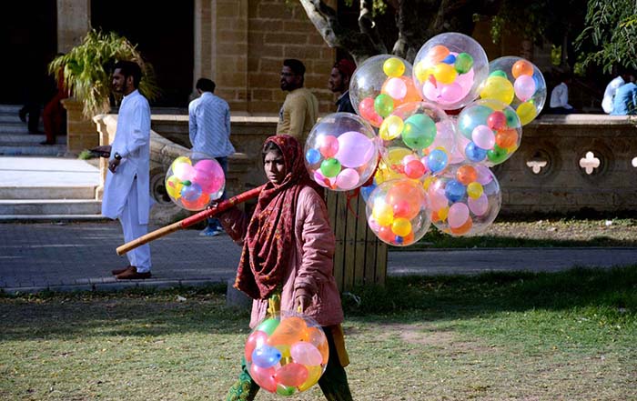 A girl selling balloons at a park.