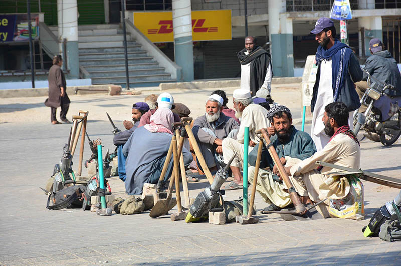 Labourers along with their tools sitting on roadside waiting for clients to be hired for work at Latifabad