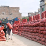 Laborers are busy unloading sacks of potatoes from delivery trucks at the Vegetable market
