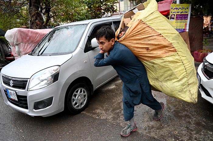 Gypsy boy on his way carrying garbage bag during rain in the Federal Capital.