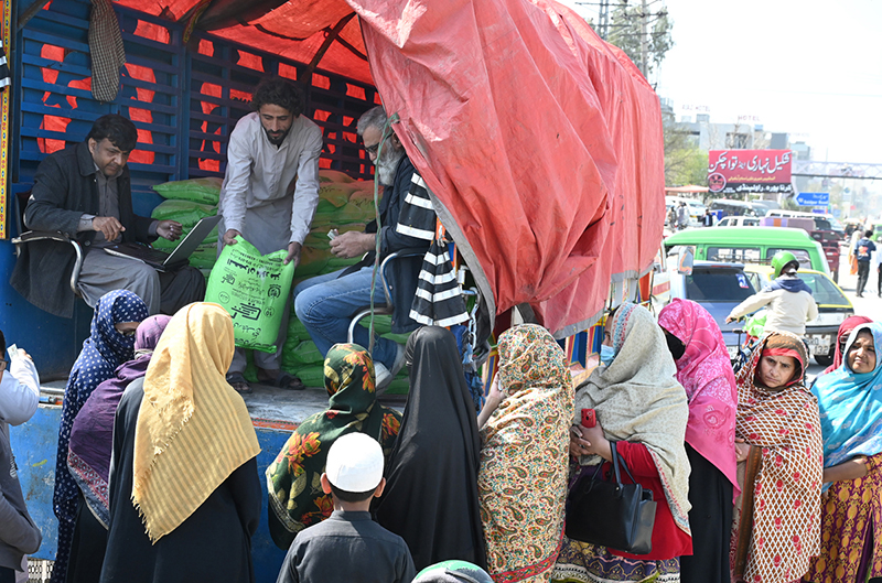 A large number of women standing in a long queue and waiting for their turn to purchase wheat flour on subsidized price provided by government in the city.