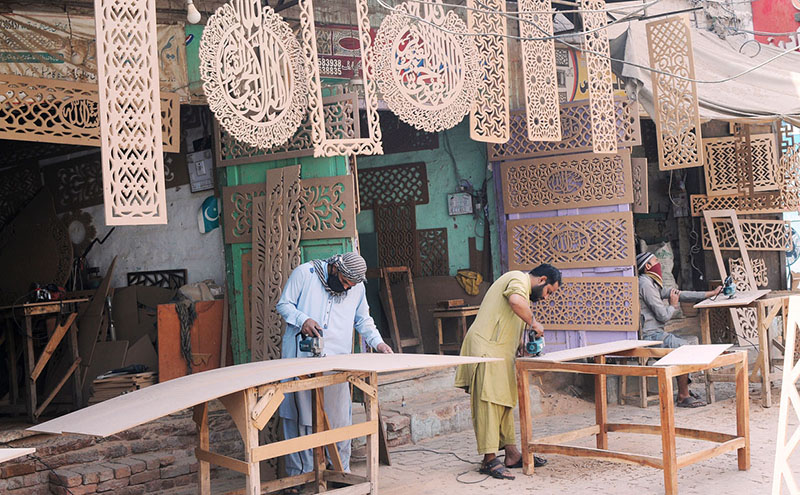 Workers are busy carving designs on the wooden sheets at their workplace