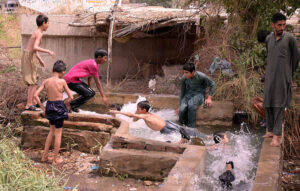Youngsters enjoying bathing in the tube-well to get relief from hot weather in the city.