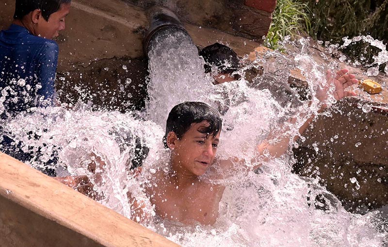 Youngsters enjoying bathing in the tube-well to get relief from hot weather in the city.