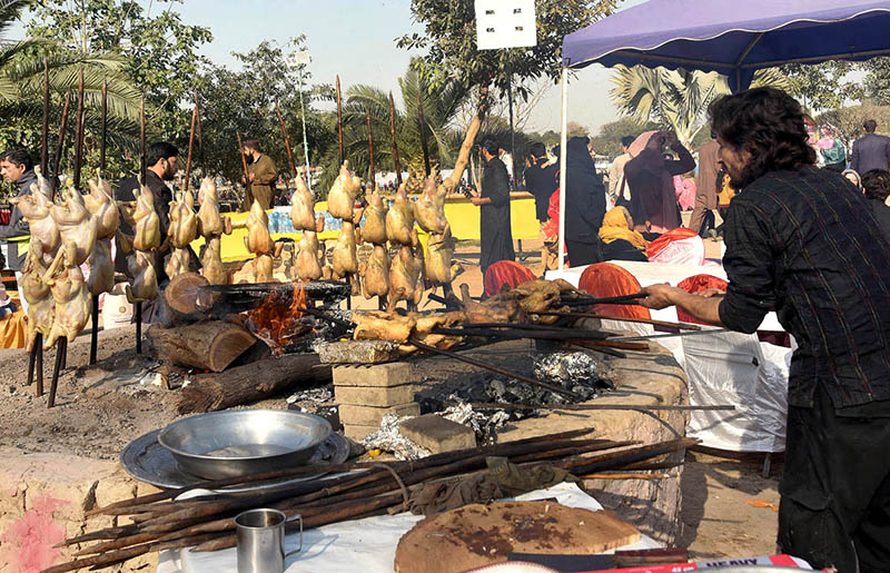 A worker prepares chicken saji over the fire during Jashan Baharan Festival at Jilani Park