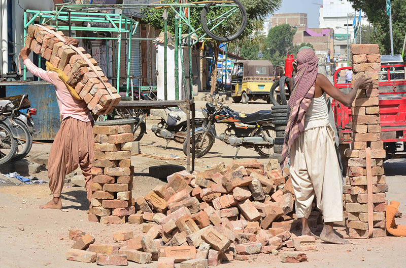 Labourers busy shifting bricks during construction work of a house at Latifabad.