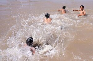 Youngsters taking bath in a canal during hot day in the city.
