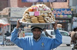 A vendor displaying different sweet items to attract customers while shuttling on the road.