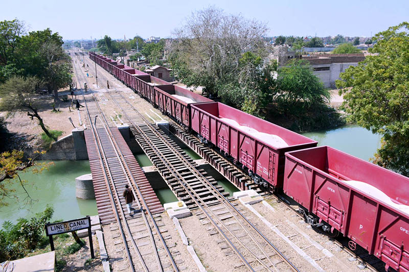 A view of goods train passing through bridge on the water canal.