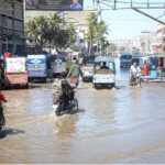 Motorcycles and rickshaw passing through rain water accumulated on the Korangi Road after rain that experienced the Provincial Capital.